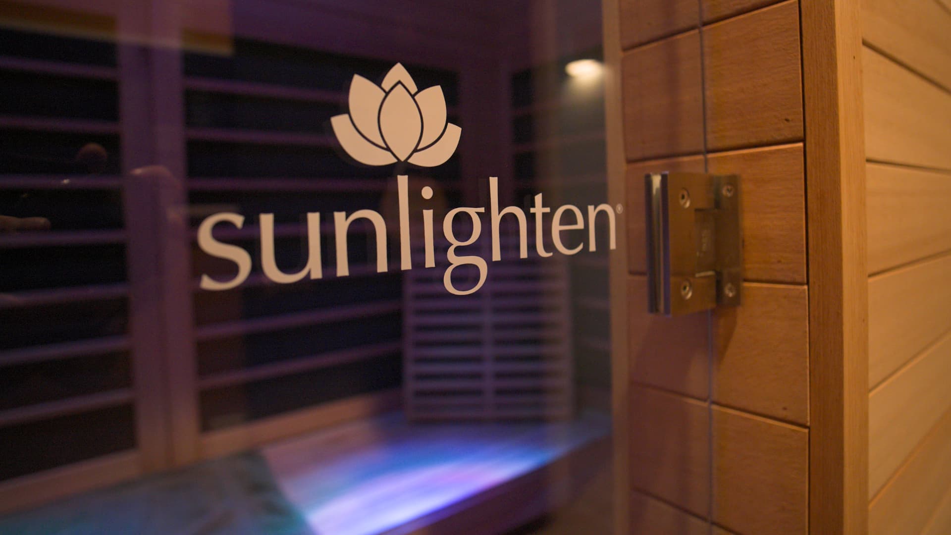 Glass door of a Sunlighten infrared sauna with cedar walls and violet chromotherapy light inside