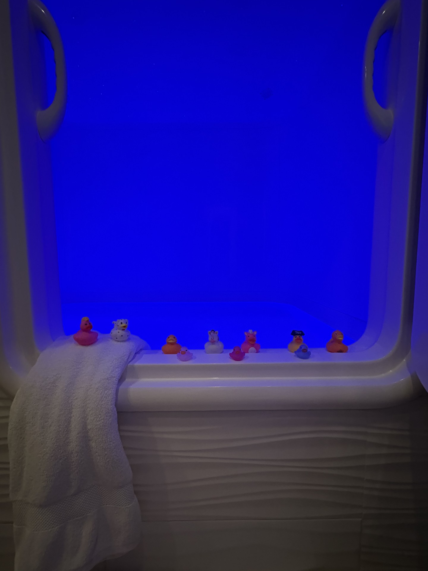 Private float cabin glowing blue with a row of colorful rubber ducks on the edge